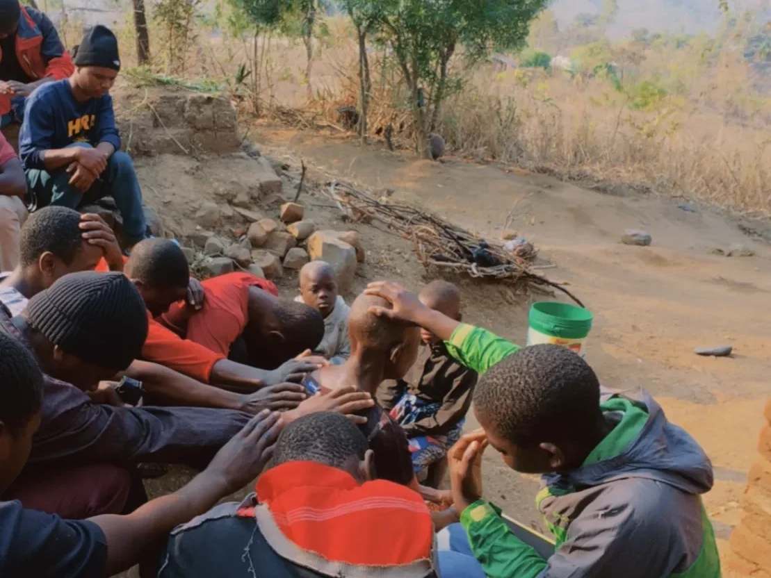 Young people praying for an elderly woman.