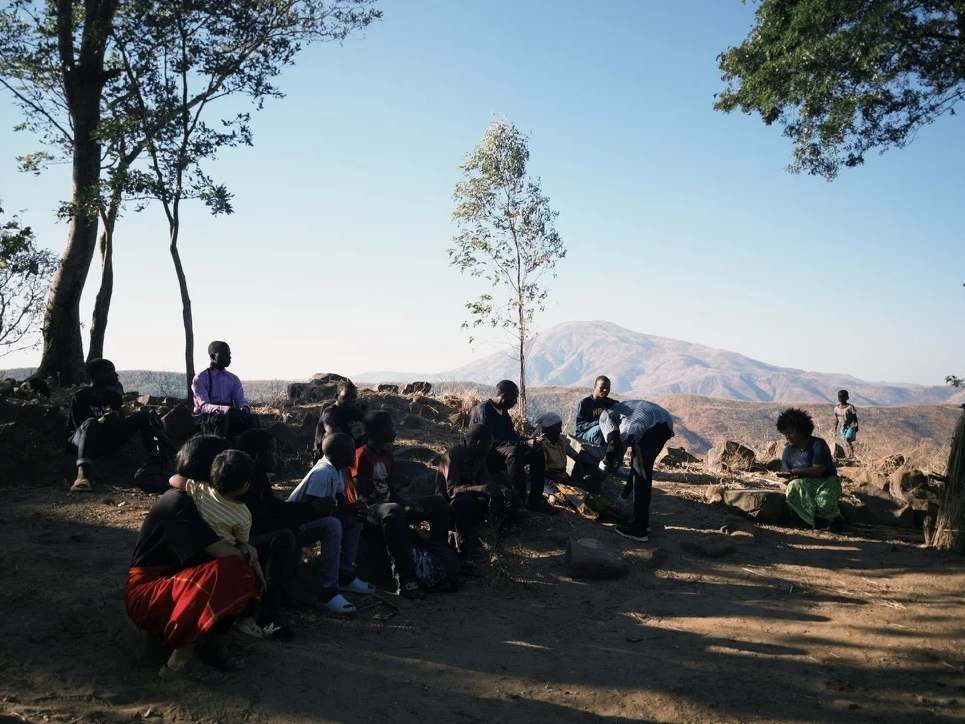 Jovens e adolescentes sentados observando o cuidado de um idoso